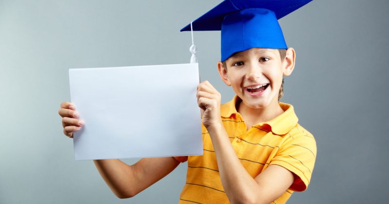 Portrait of happy boy with blank paper looking at camera